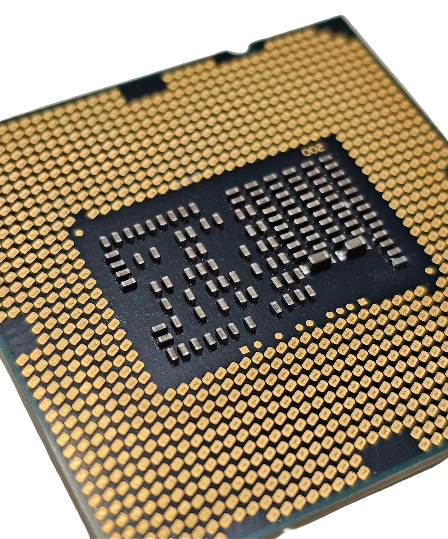 Close-up of a computer processor with gold contacts on a gray background