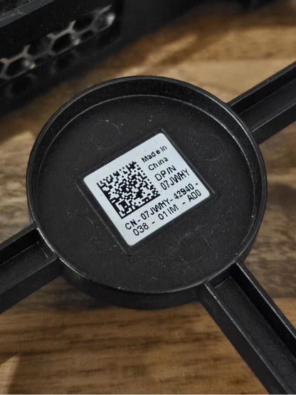 Black plastic component with a QR code label on a wooden surface